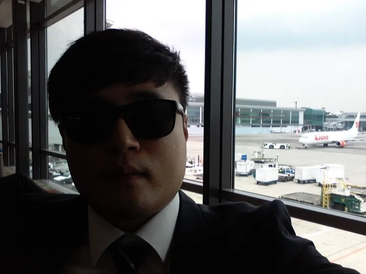 선글라스를 쓴 정장 차림 남성 공항 창가 셀카